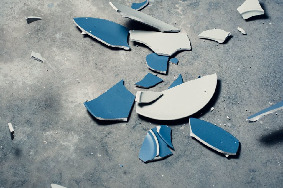 Zwei zerstörte blaue Teller auf dem Boden